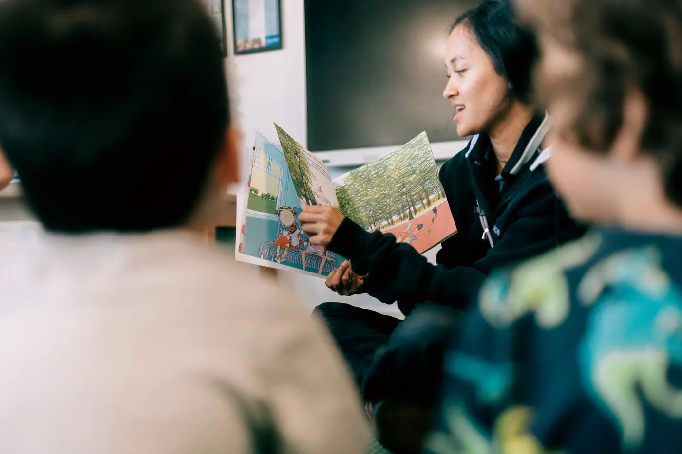 An educator reading a picture book to children